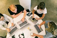 Top view of team collaborating in a modern office around laptops, discussing ideas.